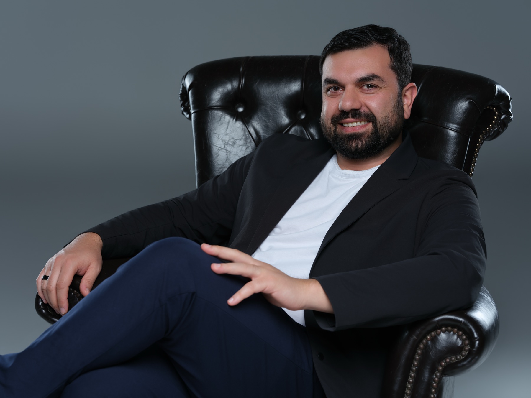 Aziz Aghayev seated in a leather armchair, relaxed and smiling